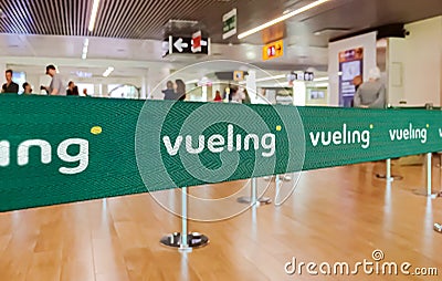 Green belt barrier with white Vueling airlines logo Editorial Stock Photo