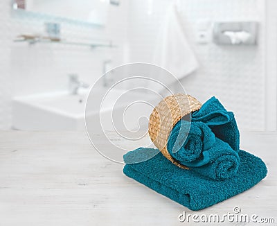 Green-blue folded towels in wicker basket over defocused bathroom Stock Photo