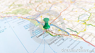 A green board pin stuck in Livorno on a map of Italy Editorial Stock Photo