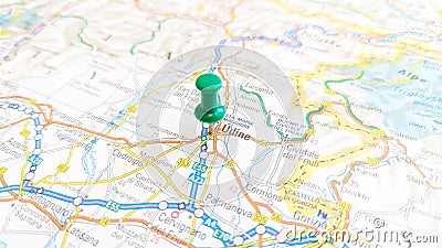 A green board pin stuck in Udine on a map of Italy Stock Photo