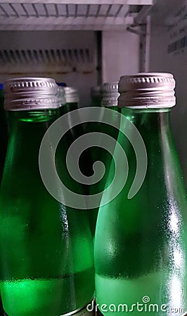 Green bottles of water same size in the refrigerator Stock Photo