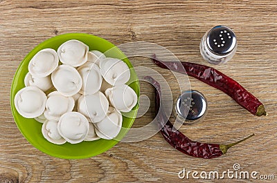 Green bowl with frozen dumplings, salt, pepper, dried chili peppers Stock Photo