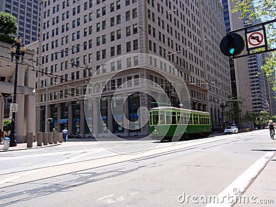 A green cable car and a biker on Market Street, one of the main thoroughfares in San Francisco Editorial Stock Photo