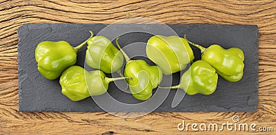 Green cambuci peppers on a stone board over wooden table. Typical brazilian ingredient Stock Photo