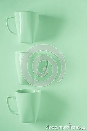 3 green coffee mugs on green background in a vertical row with empty copyspace Stock Photo