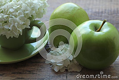 In the green cup there is a magnificent inflorescence of white flowers, and next to a green pear with an apple Stock Photo