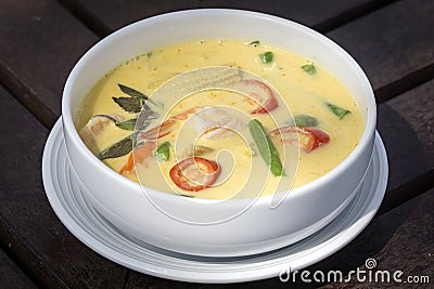 Green curry creamy soup with coconut milk, shrimp, red pepper, bean in white bowl, Thai cuisine Stock Photo