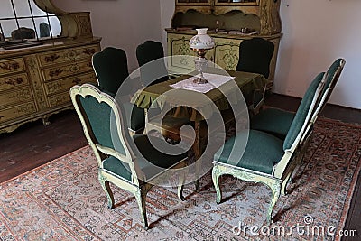 Green cushioned saloon antique nobility chairs, carved table, chest drawers, cupboards and other furniture from 19th century Stock Photo