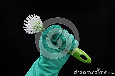 Green dishwashing brush with rubber glove isolated on black, lets work in household concept Stock Photo