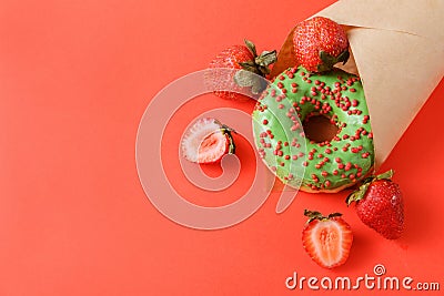 1 green donut, fresh red strawberries , paper bag on a red Stock Photo