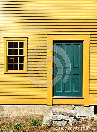 Green door on yellow exterior wall with window Stock Photo