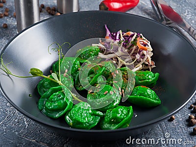 Green dumplings with vegetables in a dark dish Stock Photo