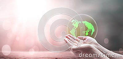 A green earth globe in human hands over blurred beautiful nature background Stock Photo