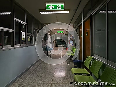 Green emergency exit sign in hospital showing the way to escape at night Stock Photo