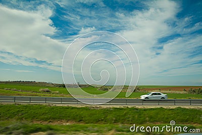 Green feilds and highway mooving cars veiw from side. The road along fields and forests Stock Photo