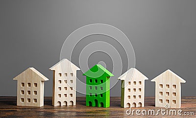 Green figure of a residential building stands out among the rest of the houses. eco-friendly and energy saving Stock Photo