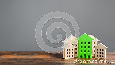 Green figure of a residential building stands out among the rest of the houses. eco-friendly and energy saving. Search Stock Photo