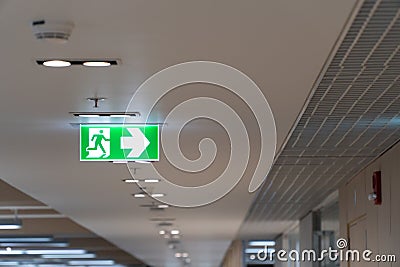 Green fire escape sign hang on the ceiling in the office. Stock Photo