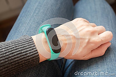 Green fitness tracker on a girls hand. Fitness bracelet for sports training. Stock Photo