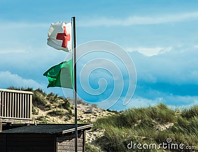 Green flag and red cross flag waving on mast at the beach Editorial Stock Photo