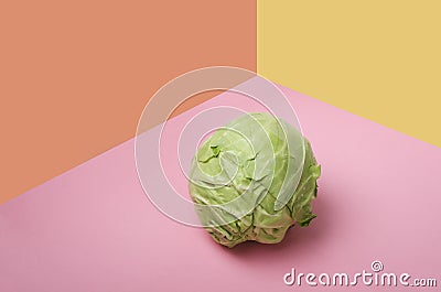 Green fresh cabbage on the pink surface, orange and yellow background.Empty space Stock Photo