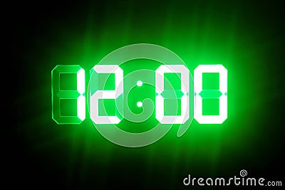 Green glowing digital clocks in the dark show 12:00 time Stock Photo