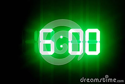 Green glowing digital clocks in the dark show 6:00 time Stock Photo