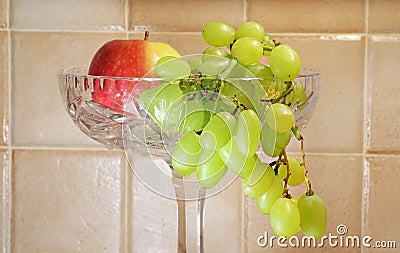 Green grapes and an apple in a crystal glass bowl Stock Photo