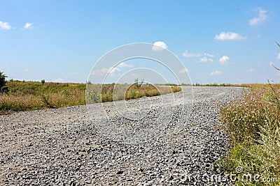 Green grass and farmlands below. A bright, sunny day. Gravel path in the fields under blue sky with clouds before sunset Stock Photo