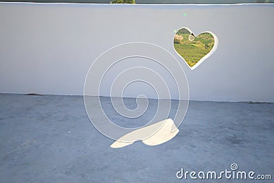 Green heart hole in white wall Stock Photo