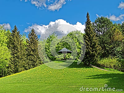Green spring landscape with bench under sun umbrella idyll Stock Photo