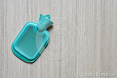 Green hot water bottle bag made of rubber on wooden table Stock Photo