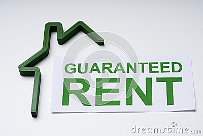 Green House Model And Paper With Guaranteed Rent Text Stock Photo