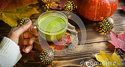 Green Japanese matcha tea with foam in transparent Cup on wooden table in autumn still life. Women`s hand with long white sweater Stock Photo