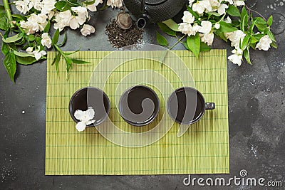 Green jasmin tea and jasmine flowers, cup of green tea on vintage grey. Top view. Teatime. Stock Photo