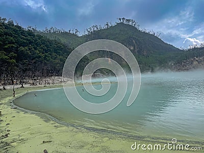 Green lake mirrored with fog above and green cliffs as a background Stock Photo