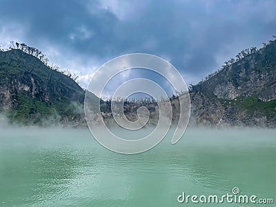 Green lake mirrored with fog above and green cliffs as a background Stock Photo