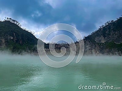 Green lake mirrored with fog above and green cliffs as a background Stock Photo