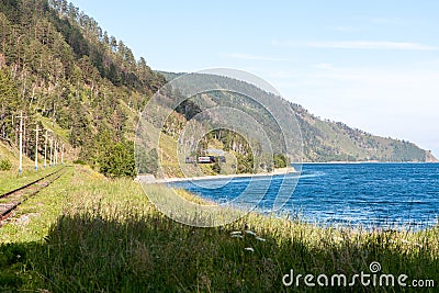 Green landscape with mountains, blue lake, forest, railway tracks and steam train Stock Photo