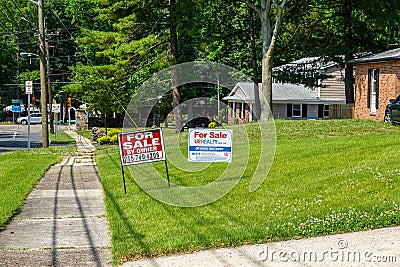 A green lawn in front of a house with two for sale signs on a sunny day Editorial Stock Photo