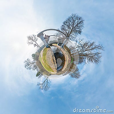 Green little tiny planet with trees near gateway lock sluice construction on river, white clouds and soft blue sky of amusement Stock Photo