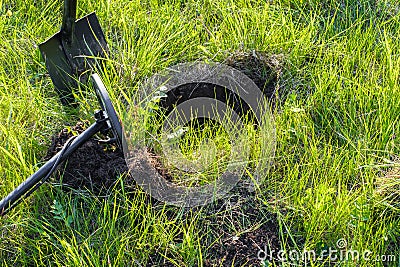 On a green meadow with grass thrown a metal detector and shovel Stock Photo