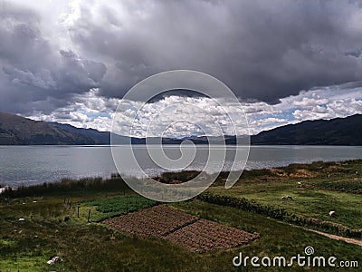 Green meadow near lagoon and distant mountains Stock Photo