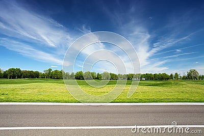 Green meadow with trees and asphalt road Stock Photo