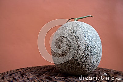 Green melon fruit close up. on grille bamboo and Brown color cement wall in studio Stock Photo