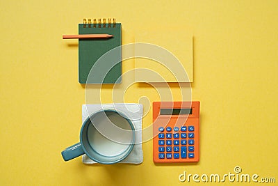 Green notepad, memo paper, color pencil, cup of milk, calculator isolated on yellow background. flat lay, top view, copy space Stock Photo