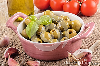 Green olive in a pink bowl, garlic, tomatoes and olive oil in a Stock Photo