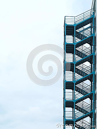 Green outside fire escape stairs ladder over cloudy sky Stock Photo