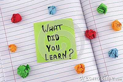A green paper note with the question What did you learn on it on a notebook sheet with some colorful crumpled paper balls around Stock Photo