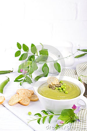 Green pea soup puree with croutons in black bowl. On white background. Stock Photo